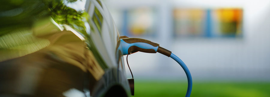 Closeup of an electric car with plugged in charger.