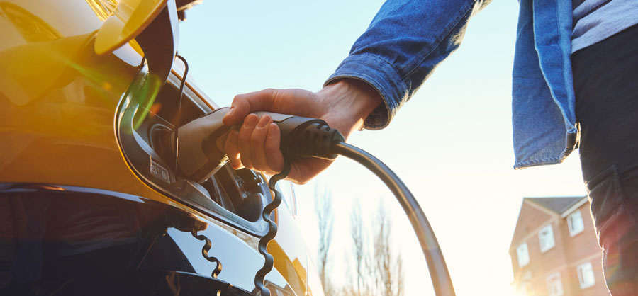 A person inserting a charging cable into an EV